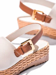 Sandales plates blanches élégantes avec semelle tressée et bride ajustable sur fond blanc