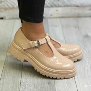 Chaussures plateforme beige vernis à bride et boucle portées avec pantalon noir
